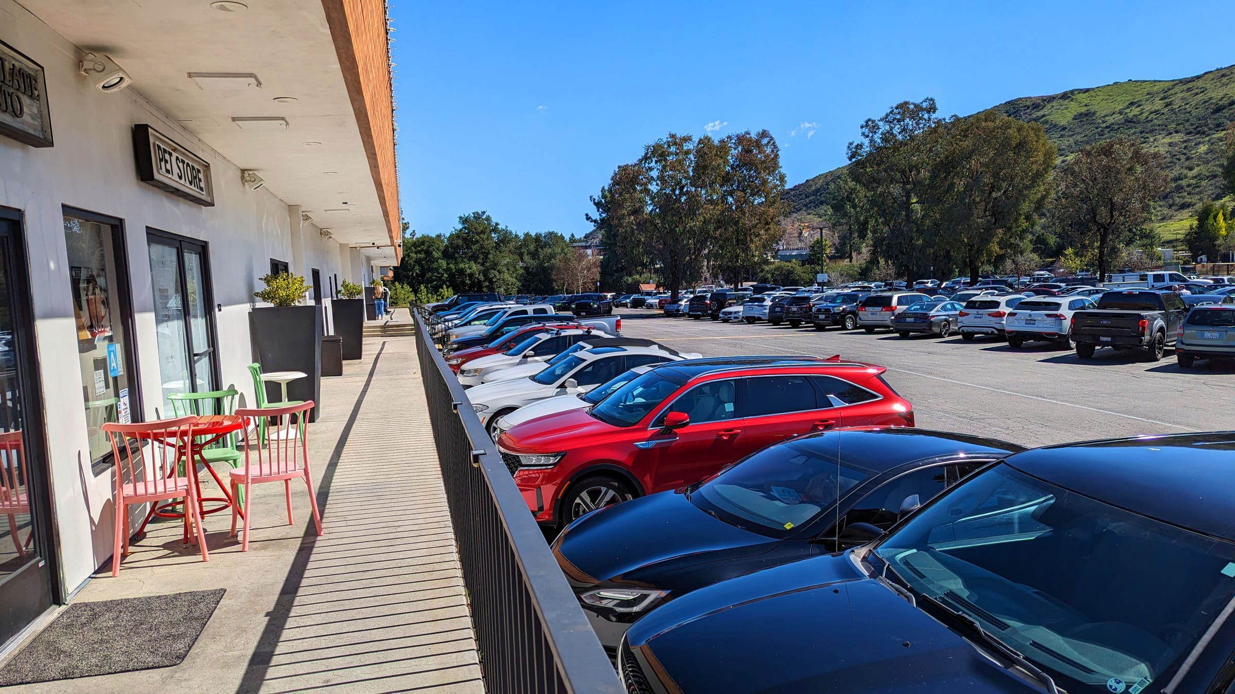 A commercial property parking lot in daylight, cars lined along a storefront